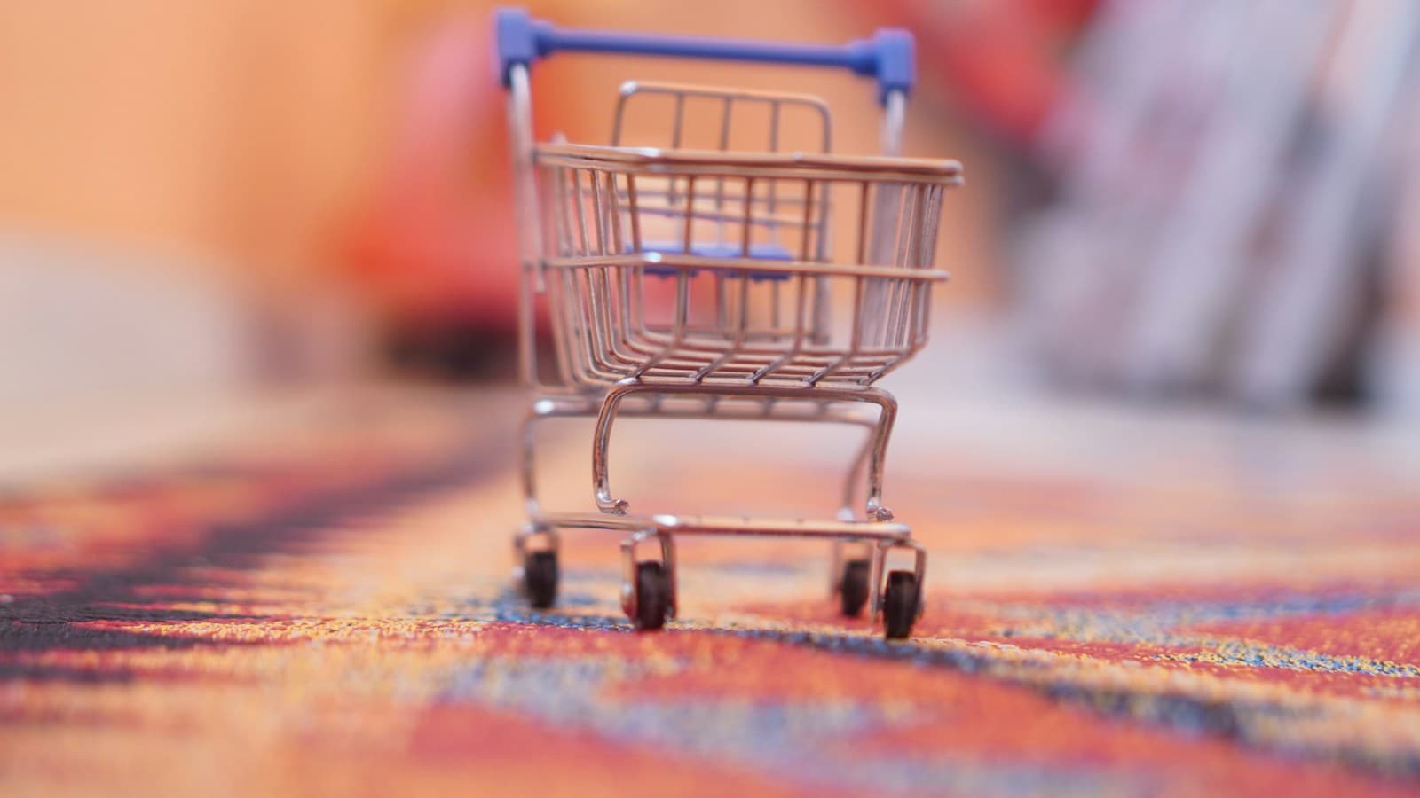 Un coș de cumpărături în miniatură, pe un covor colorat